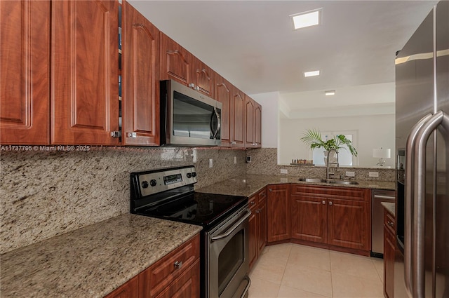 kitchen featuring light stone counters, stainless steel appliances, sink, and decorative backsplash