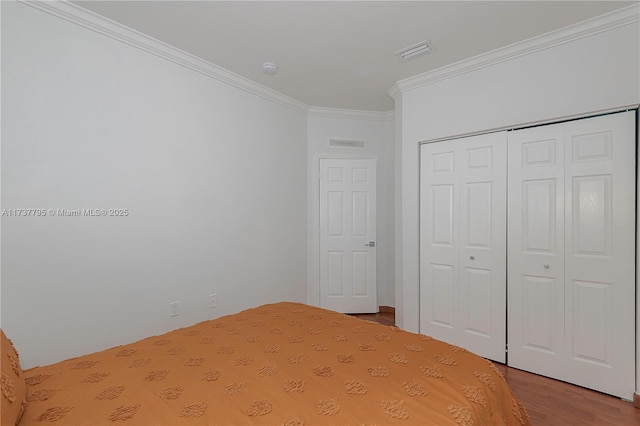 unfurnished bedroom with hardwood / wood-style flooring, ornamental molding, and a closet