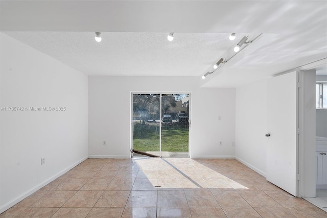 spare room with light tile patterned floors and a textured ceiling