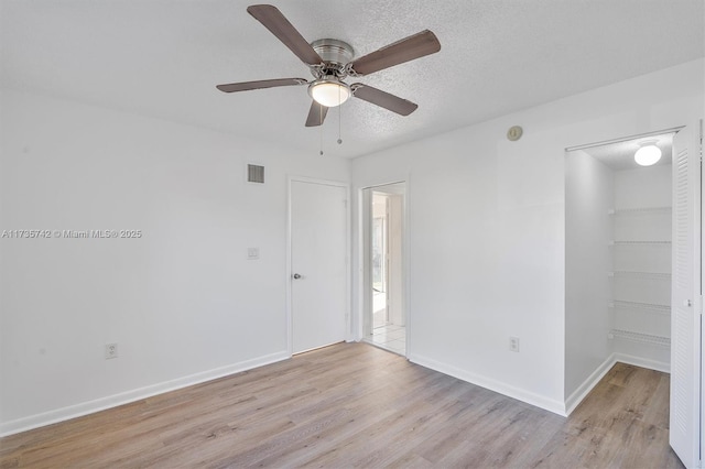 spare room with ceiling fan, light hardwood / wood-style flooring, and a textured ceiling