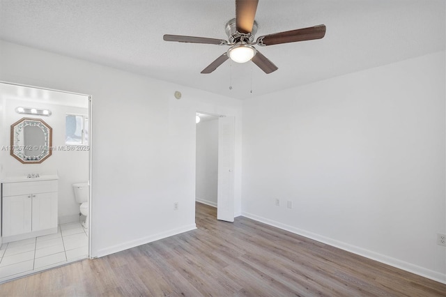 unfurnished bedroom with connected bathroom, sink, ceiling fan, and light wood-type flooring