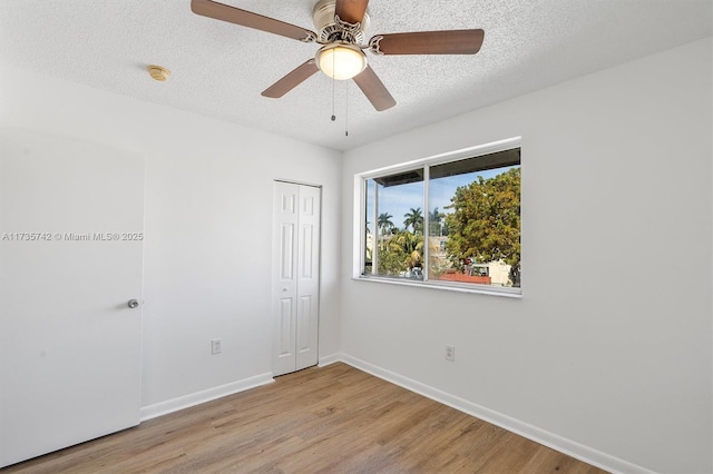 spare room with ceiling fan, a textured ceiling, and light wood-type flooring