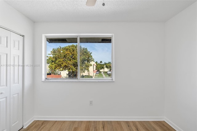 unfurnished bedroom with wood-type flooring, ceiling fan, a textured ceiling, and a closet