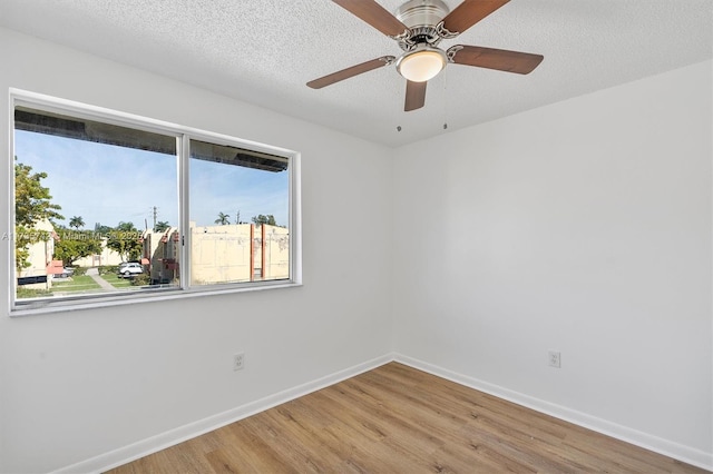 spare room with ceiling fan, a textured ceiling, wood-type flooring, and a healthy amount of sunlight