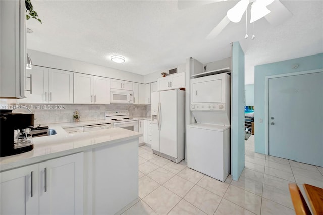 kitchen with white cabinetry, white appliances, kitchen peninsula, and stacked washer / dryer