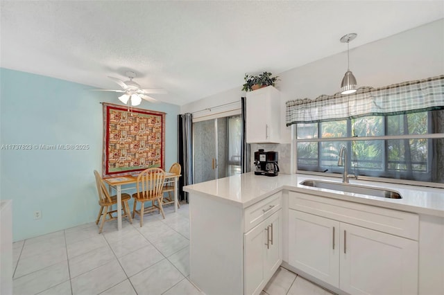 kitchen featuring sink, white cabinets, hanging light fixtures, kitchen peninsula, and a textured ceiling