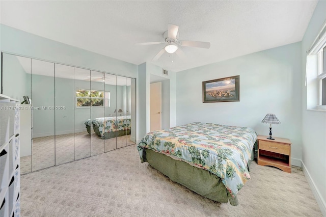 carpeted bedroom featuring multiple windows, a textured ceiling, a closet, and ceiling fan