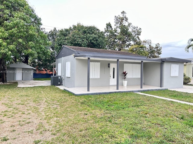 view of front of property featuring a front yard, a patio area, central air condition unit, and a storage unit