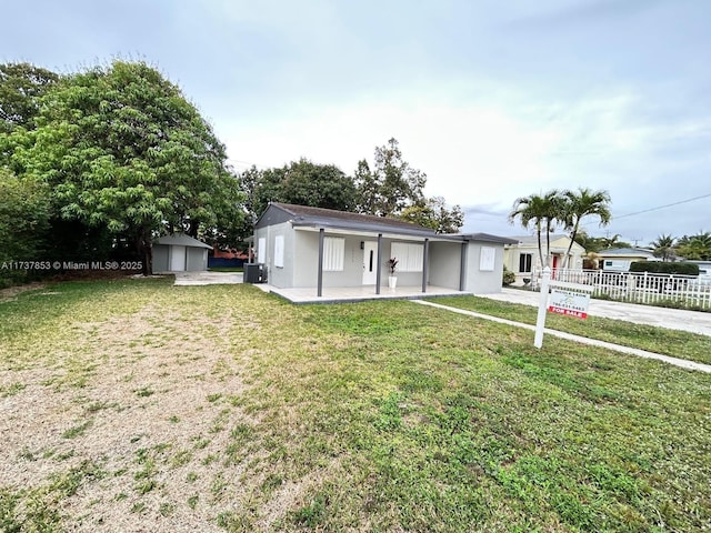 view of front of home featuring a shed, central AC unit, a front lawn, and a patio