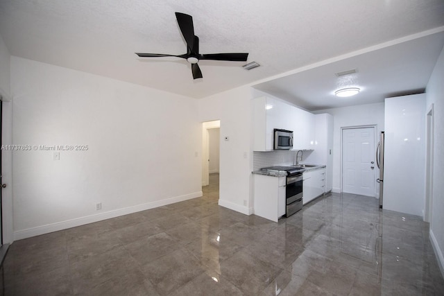 kitchen featuring sink, ceiling fan, appliances with stainless steel finishes, white cabinets, and decorative backsplash