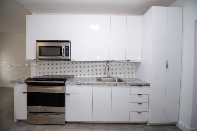 kitchen featuring sink, appliances with stainless steel finishes, white cabinetry, light stone counters, and tasteful backsplash