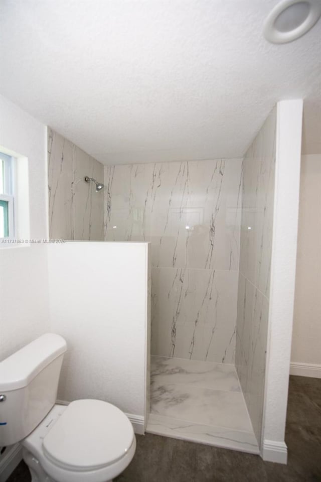 bathroom with tiled shower, toilet, and a textured ceiling