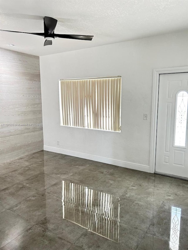 foyer entrance with ceiling fan and a textured ceiling