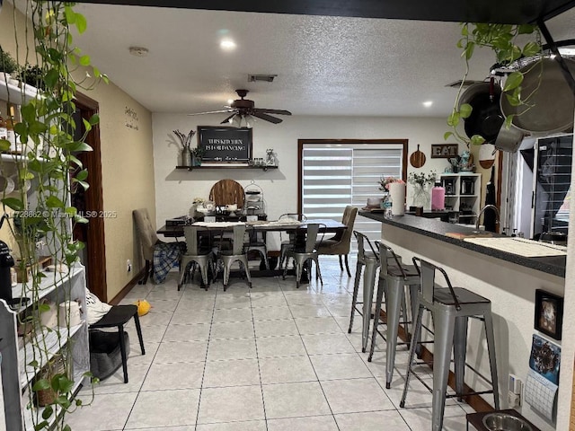 tiled dining room with ceiling fan and a textured ceiling