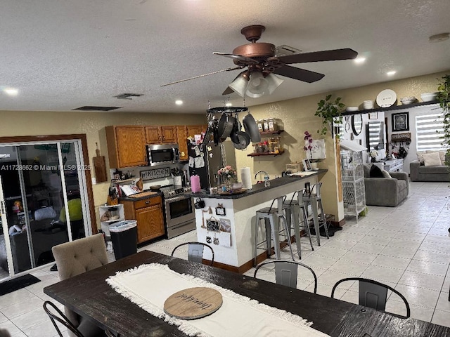 dining area featuring light tile patterned floors, a textured ceiling, and ceiling fan