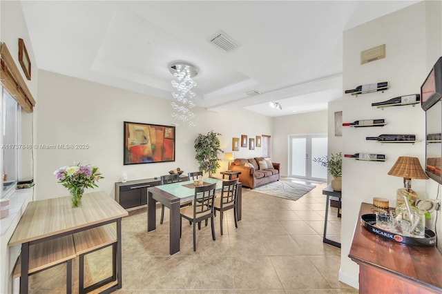 dining area with light tile patterned floors and a tray ceiling