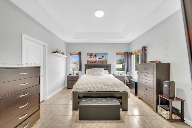 bedroom featuring light tile patterned flooring, a tray ceiling, and multiple windows