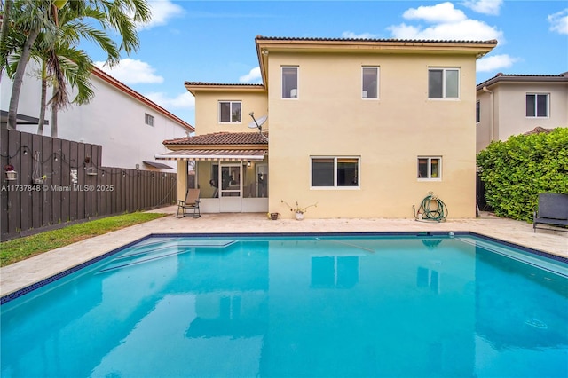 rear view of house with a sunroom, a fenced in pool, and a patio