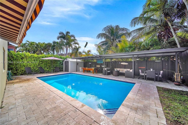 view of pool featuring a storage unit, outdoor lounge area, and a patio area