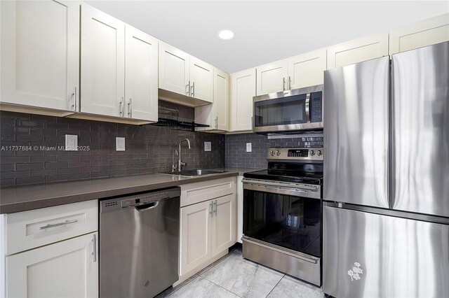 kitchen with tasteful backsplash, sink, stainless steel appliances, and white cabinets