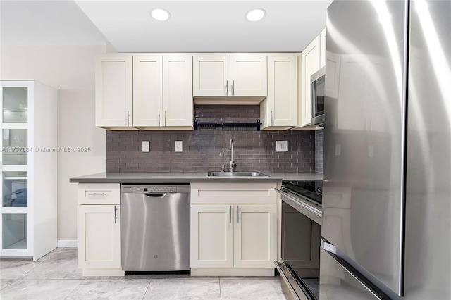 kitchen with white cabinetry, stainless steel appliances, sink, and decorative backsplash