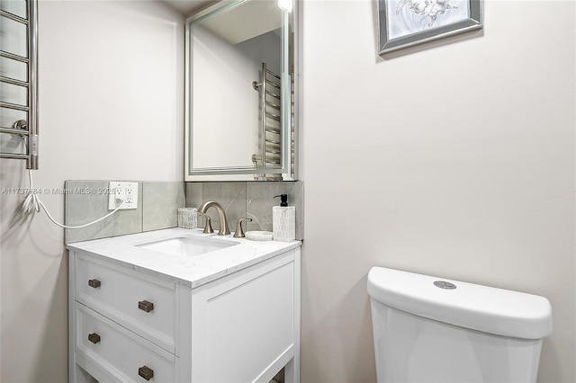 bathroom featuring vanity, backsplash, and toilet