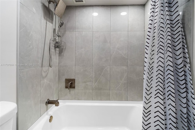 bathroom featuring tiled shower / bath and toilet