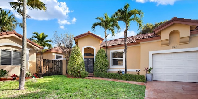 mediterranean / spanish house featuring a front yard, an attached garage, fence, and stucco siding