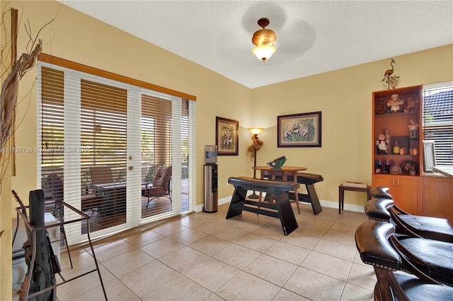 dining space featuring light tile patterned flooring, a ceiling fan, and baseboards