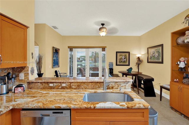 kitchen featuring light stone counters, dishwasher, a peninsula, and a sink