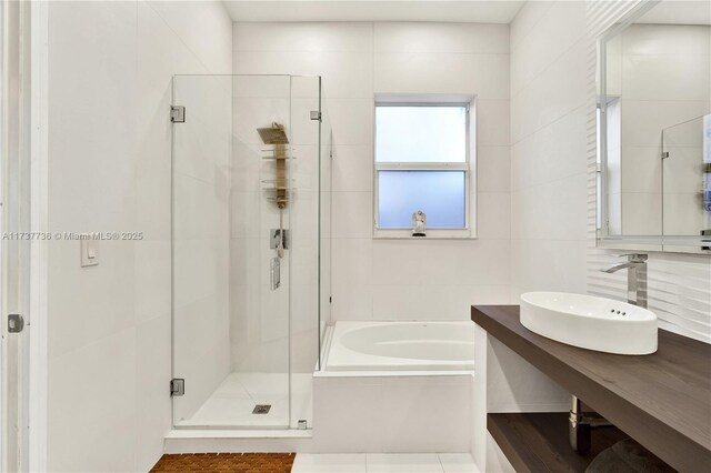 bathroom featuring plus walk in shower, tile walls, vanity, and decorative backsplash