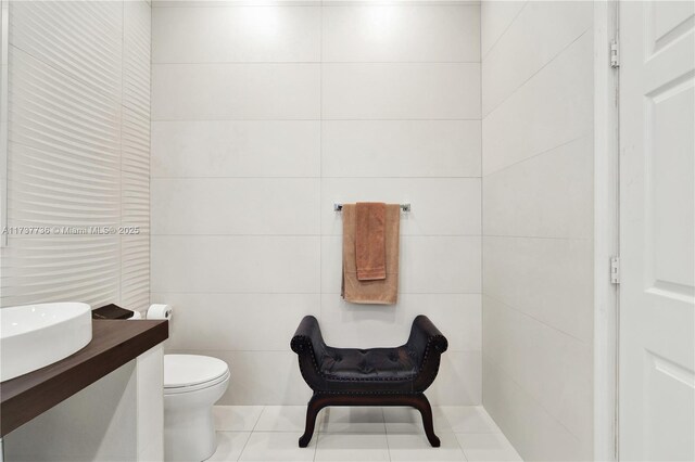 bathroom featuring tile patterned flooring, vanity, tile walls, and toilet