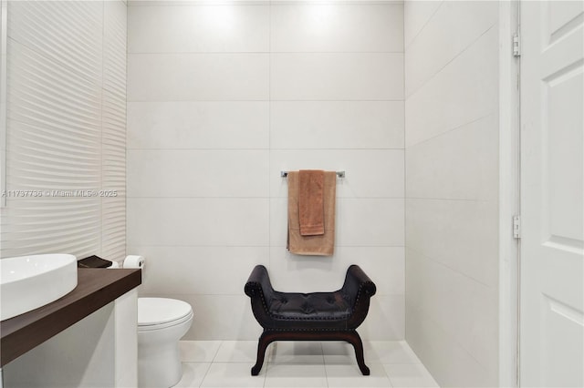 bathroom with toilet, tile patterned flooring, tile walls, and vanity