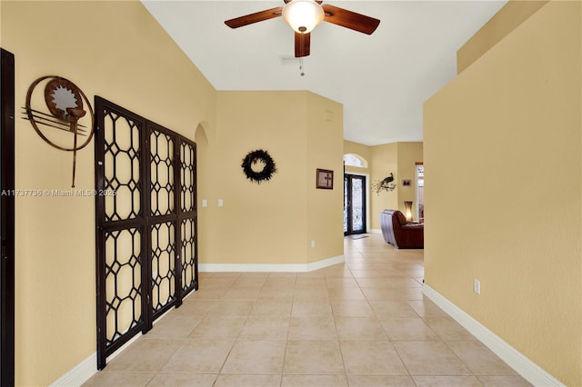 hall with light tile patterned floors, arched walkways, and baseboards