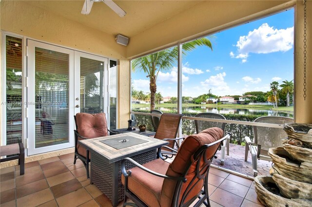 sunroom featuring ceiling fan and a water view