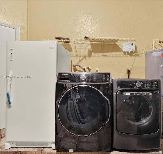 washroom featuring laundry area, a textured wall, and washing machine and clothes dryer