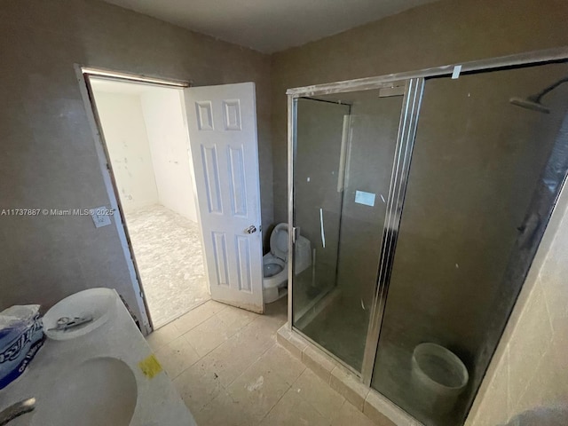 bathroom featuring toilet and a shower with shower door