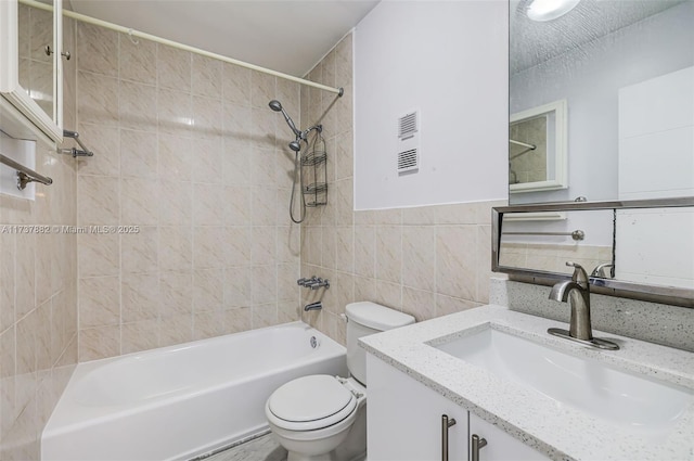 full bathroom featuring tiled shower / bath combo, vanity, tile walls, and toilet