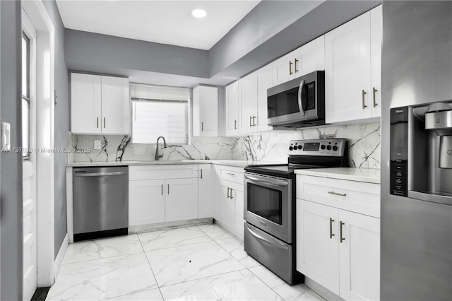 kitchen featuring decorative backsplash, white cabinets, and appliances with stainless steel finishes