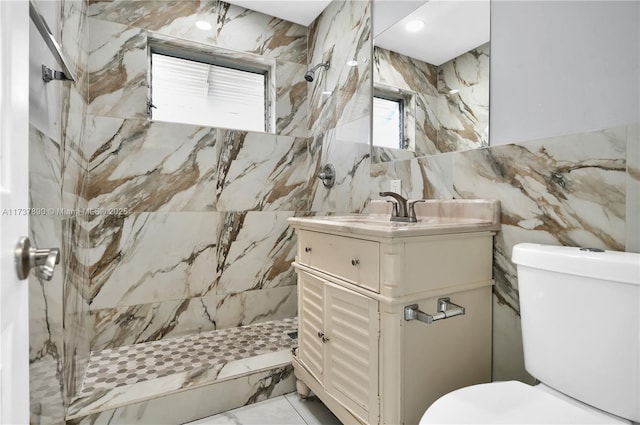 bathroom with vanity, tile walls, toilet, and tiled shower