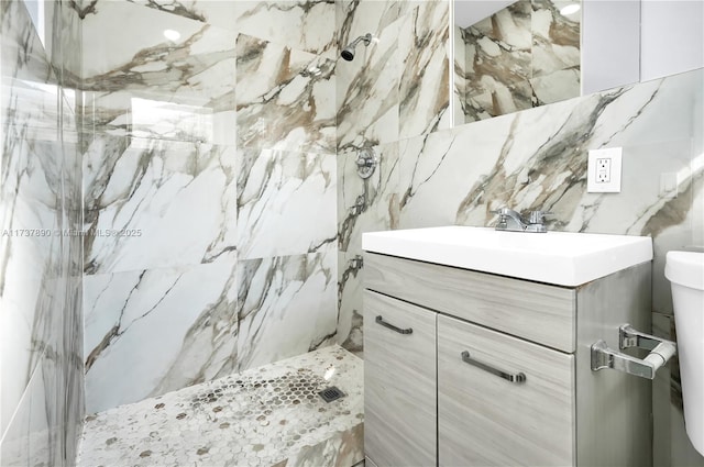 bathroom with vanity, tiled shower, and toilet