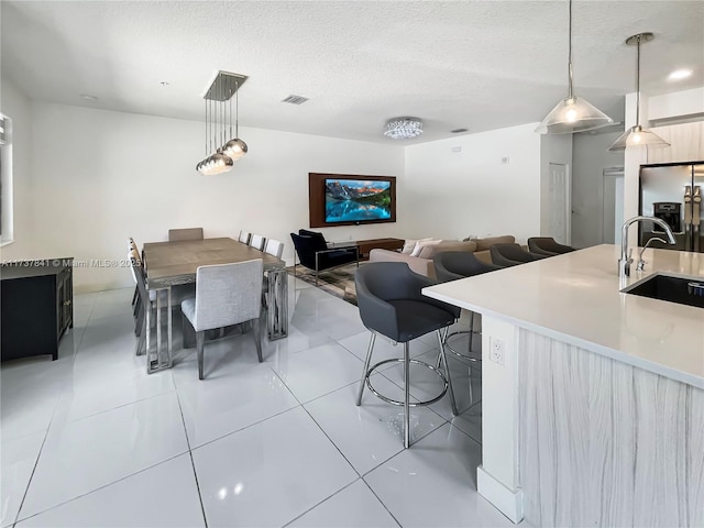 dining area featuring light tile patterned floors, visible vents, and a textured ceiling