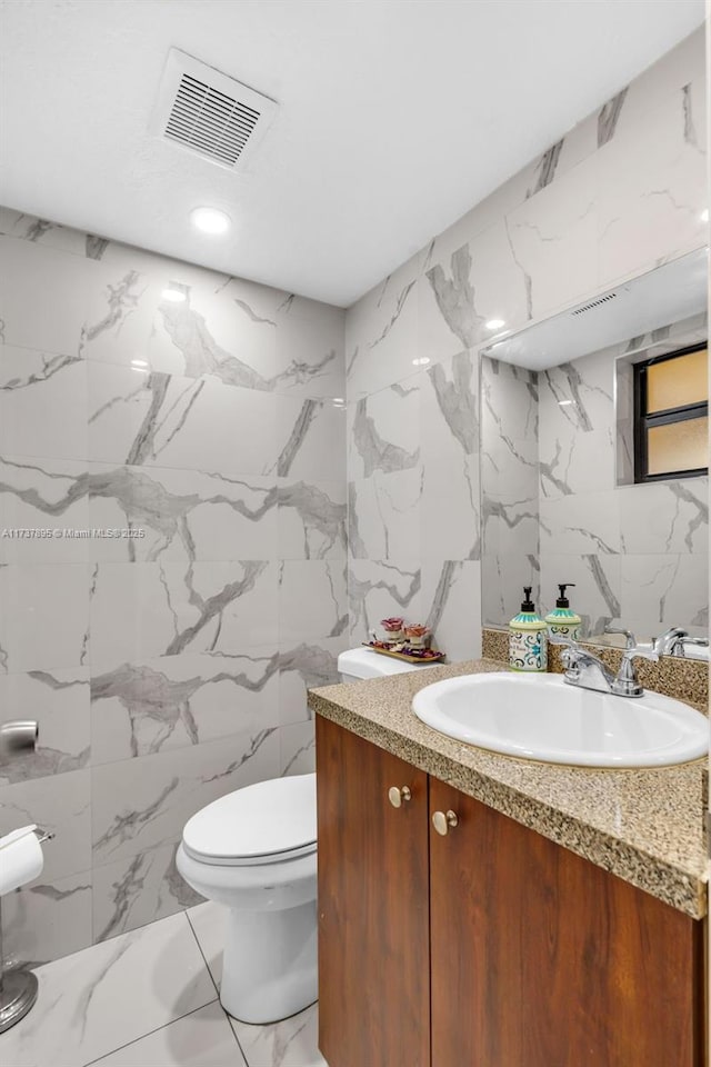 bathroom with vanity, tile walls, and toilet