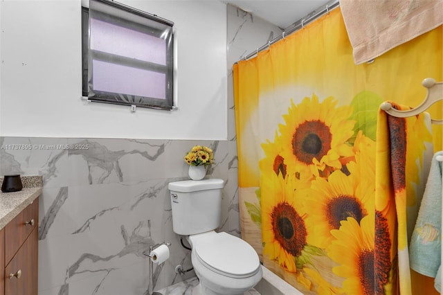 bathroom featuring vanity, tile walls, toilet, and walk in shower