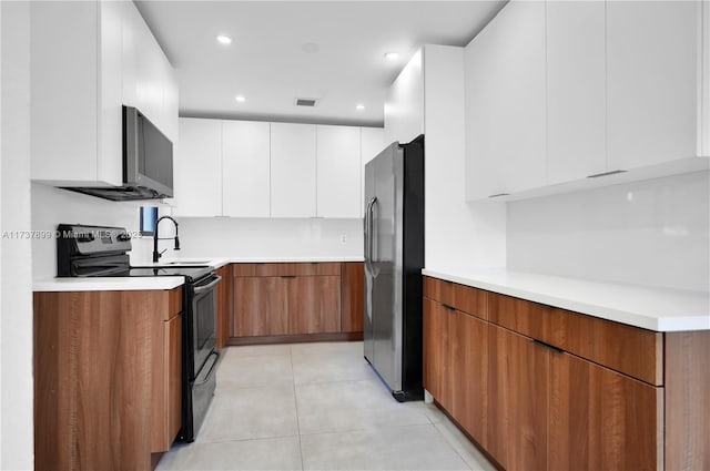 kitchen with stainless steel appliances, light tile patterned floors, and white cabinets