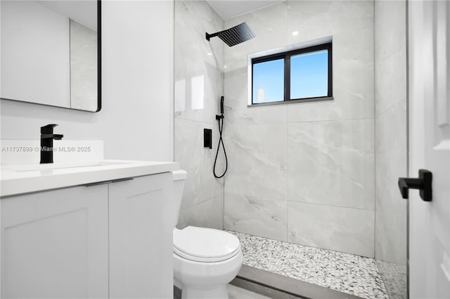 bathroom featuring vanity, tiled shower, and toilet