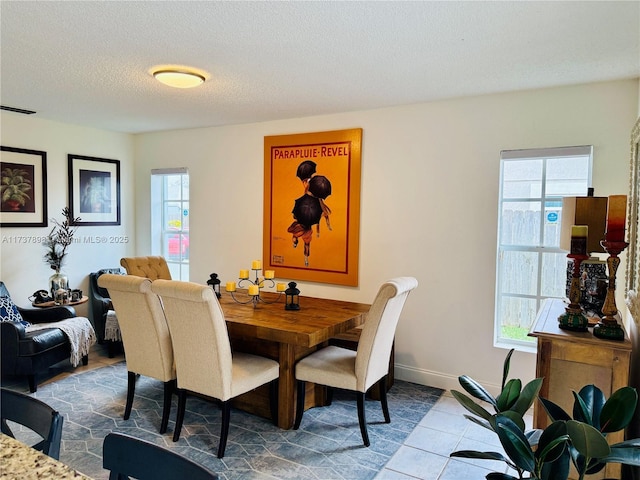 dining room with tile patterned floors, a healthy amount of sunlight, and a textured ceiling