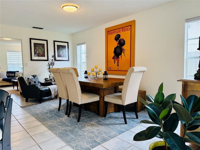 dining space featuring light tile patterned floors and a textured ceiling