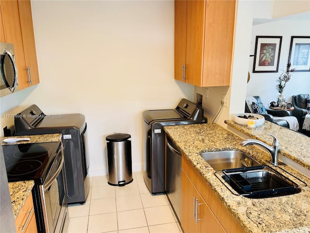 clothes washing area featuring separate washer and dryer, sink, and light tile patterned floors