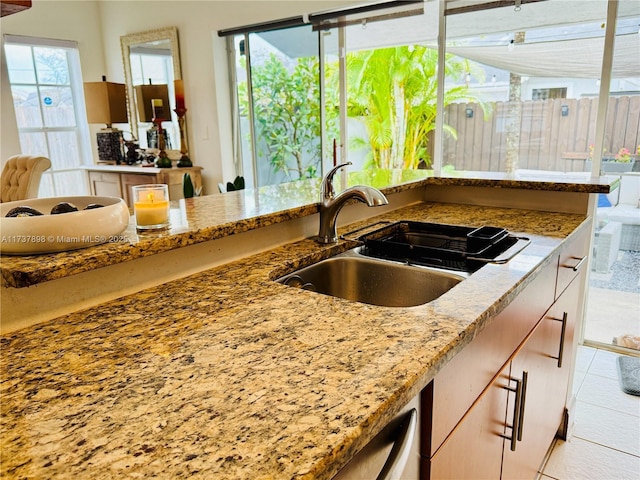 kitchen with light tile patterned flooring, sink, and light stone counters